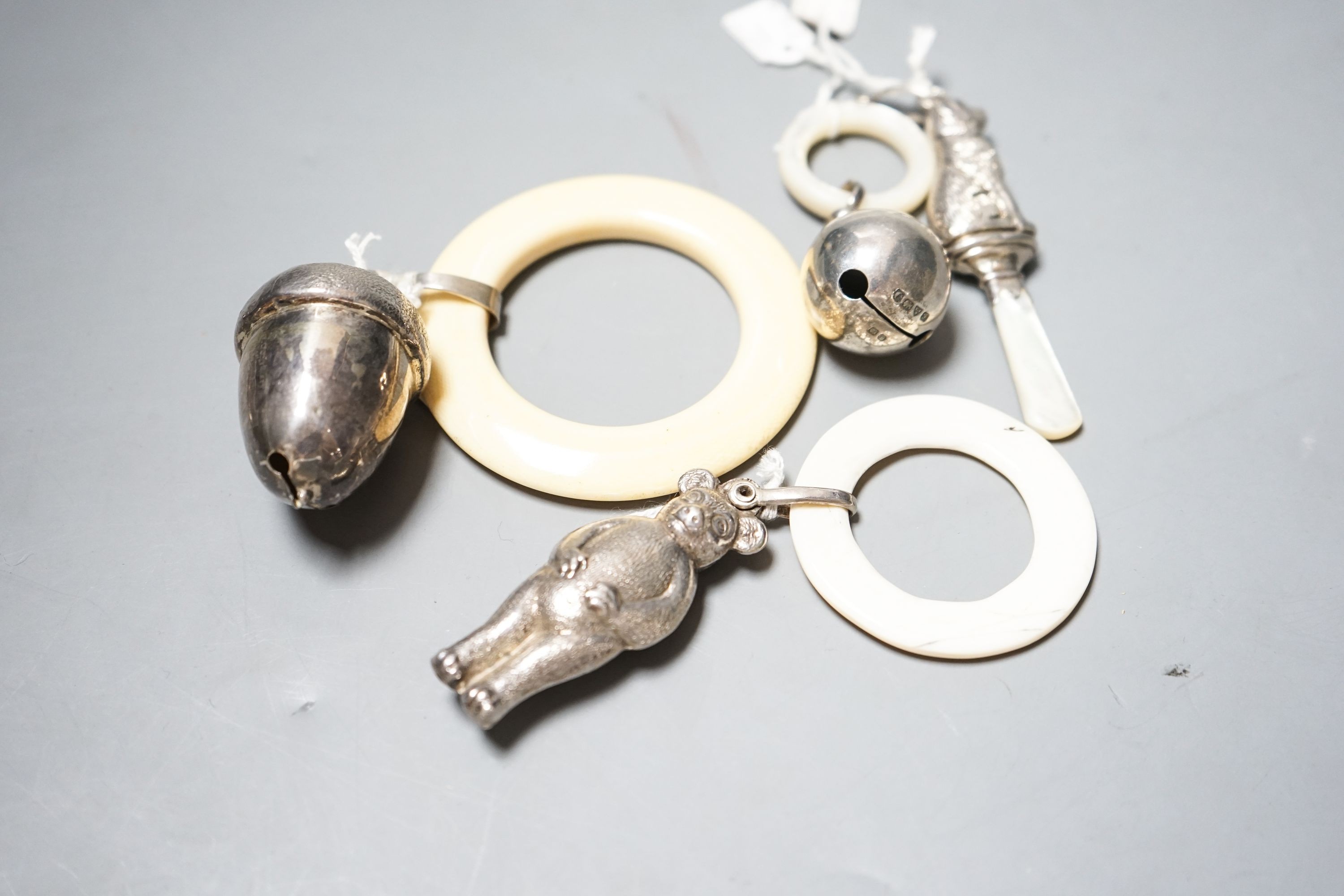 Four assorted child's silver and white metal teething rattles, including dog, bear and acorn.